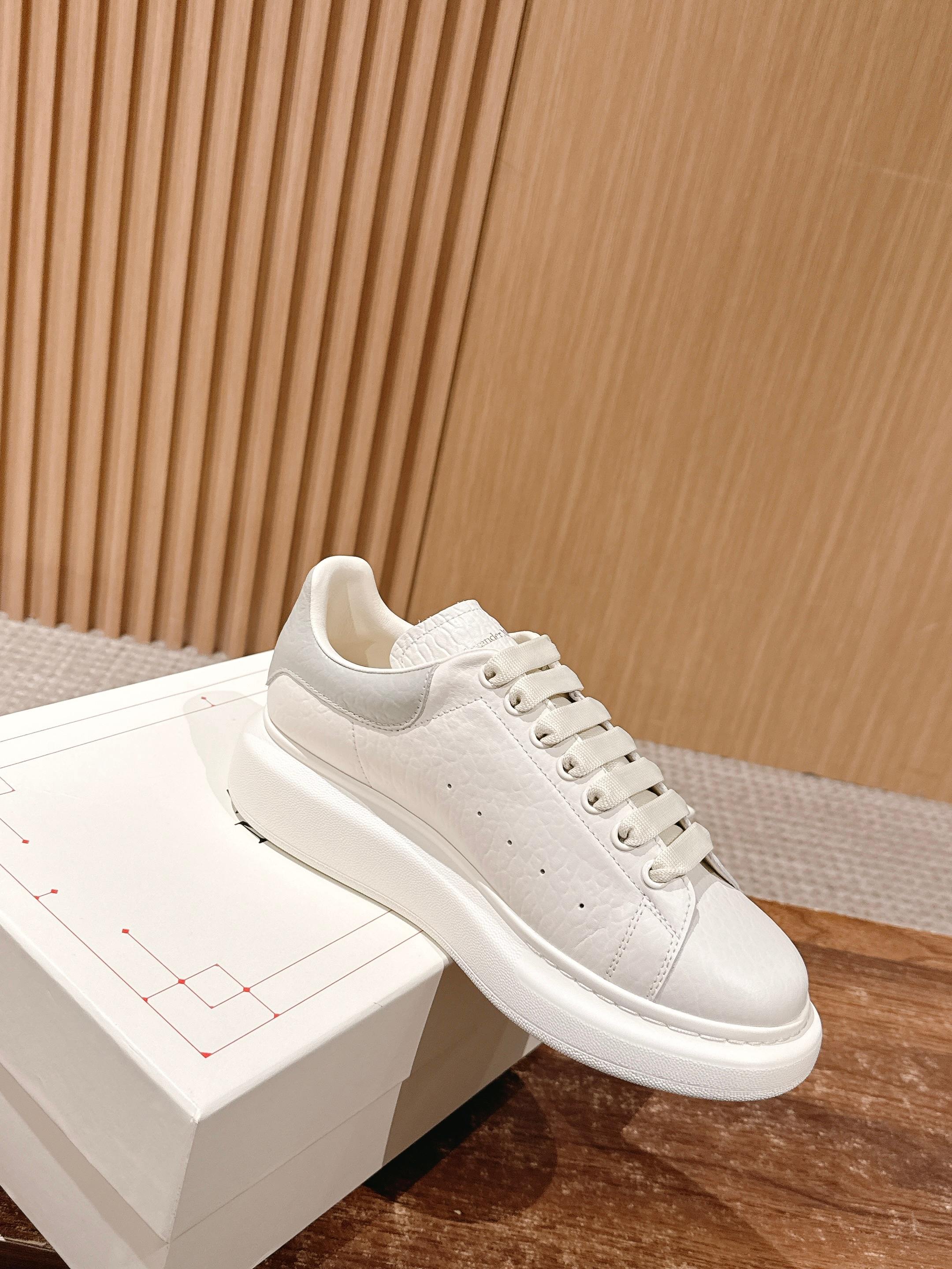 Alexander McQueen leather sneakers, white, angled side view on display box