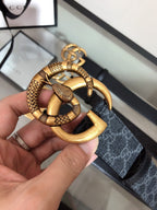 Belt buckle close-up: gold ring with snakeskin-style trim on black strap