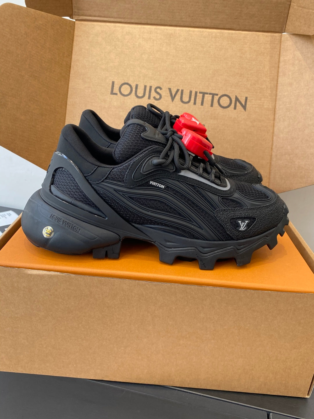 Black lace-up sneakers with rugged sole and red LV heart logo accents