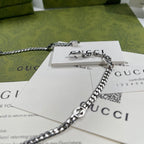 Silver-tone chain necklace with round pendant and logo charm, close-up