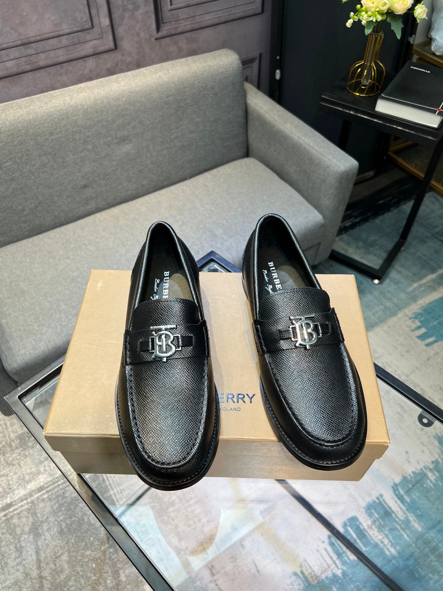 Burberry logo loafers, dark leather with metal emblem and apron toe stitching, front view
