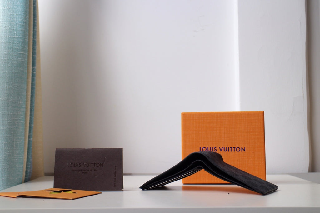 Folded Louis Vuitton wallet with dark exterior and black strap