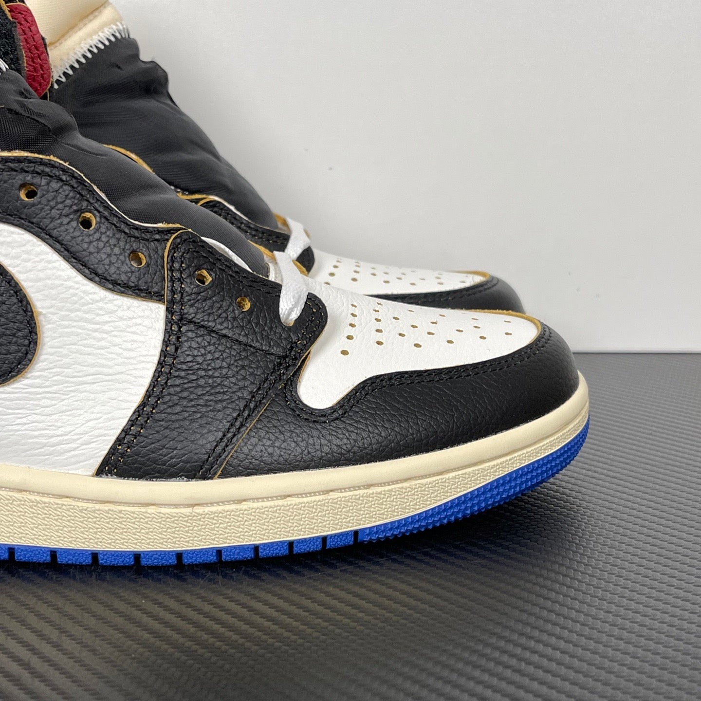 High-top sneaker close-up, black and white leather with blue outsole and gold eyelets