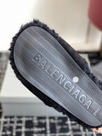 Black fuzzy slide sandal outsole with embossed logo pattern, close-up
