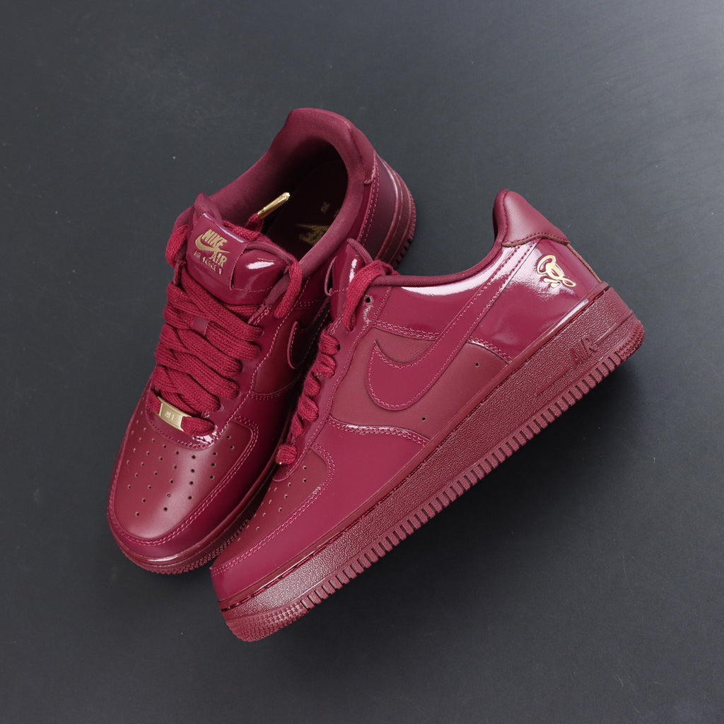 Burgundy low-top sneakers pair, angled top view with Nike swoosh and lace-up