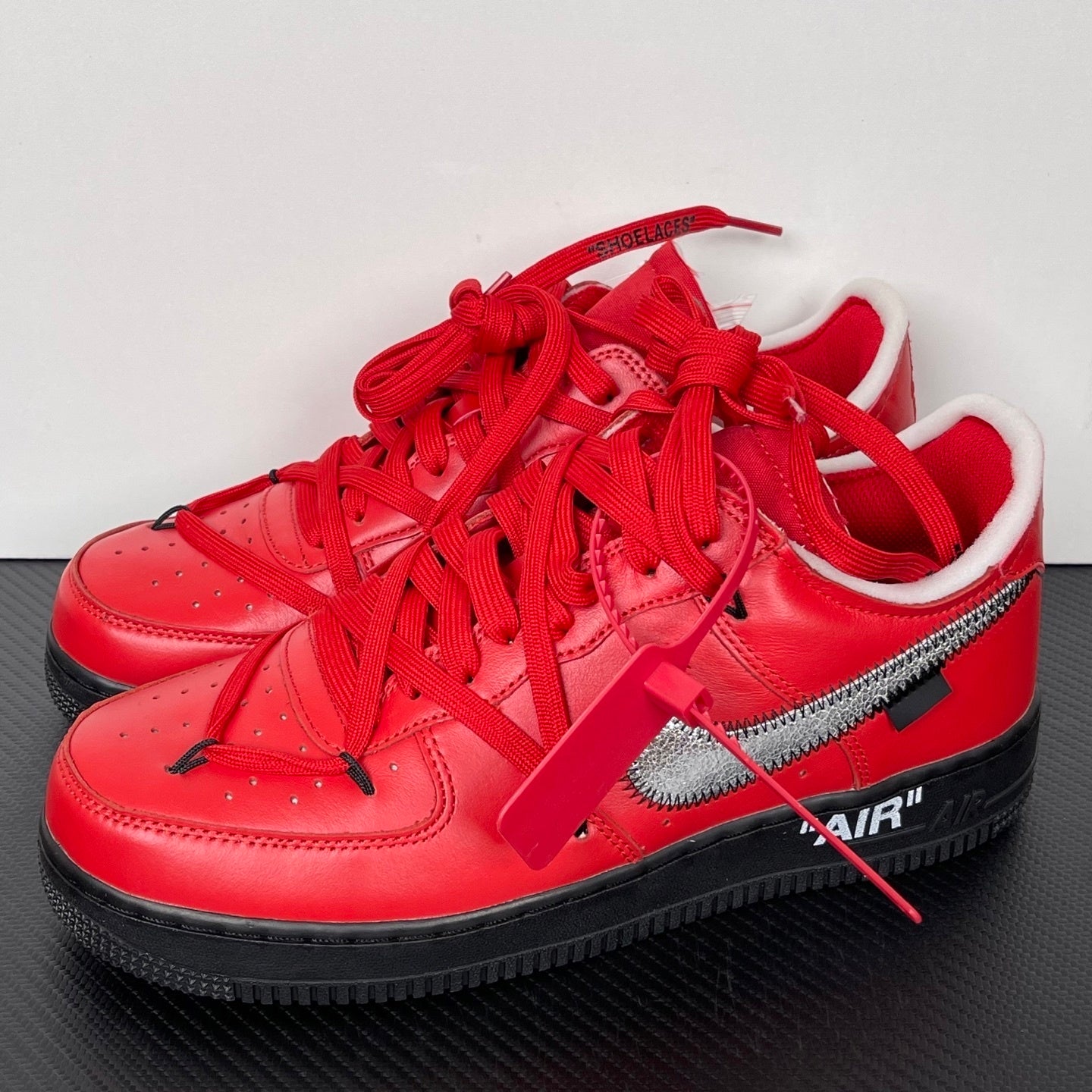 Pair of red low-top sneakers with red laces and silver swoosh, black sole