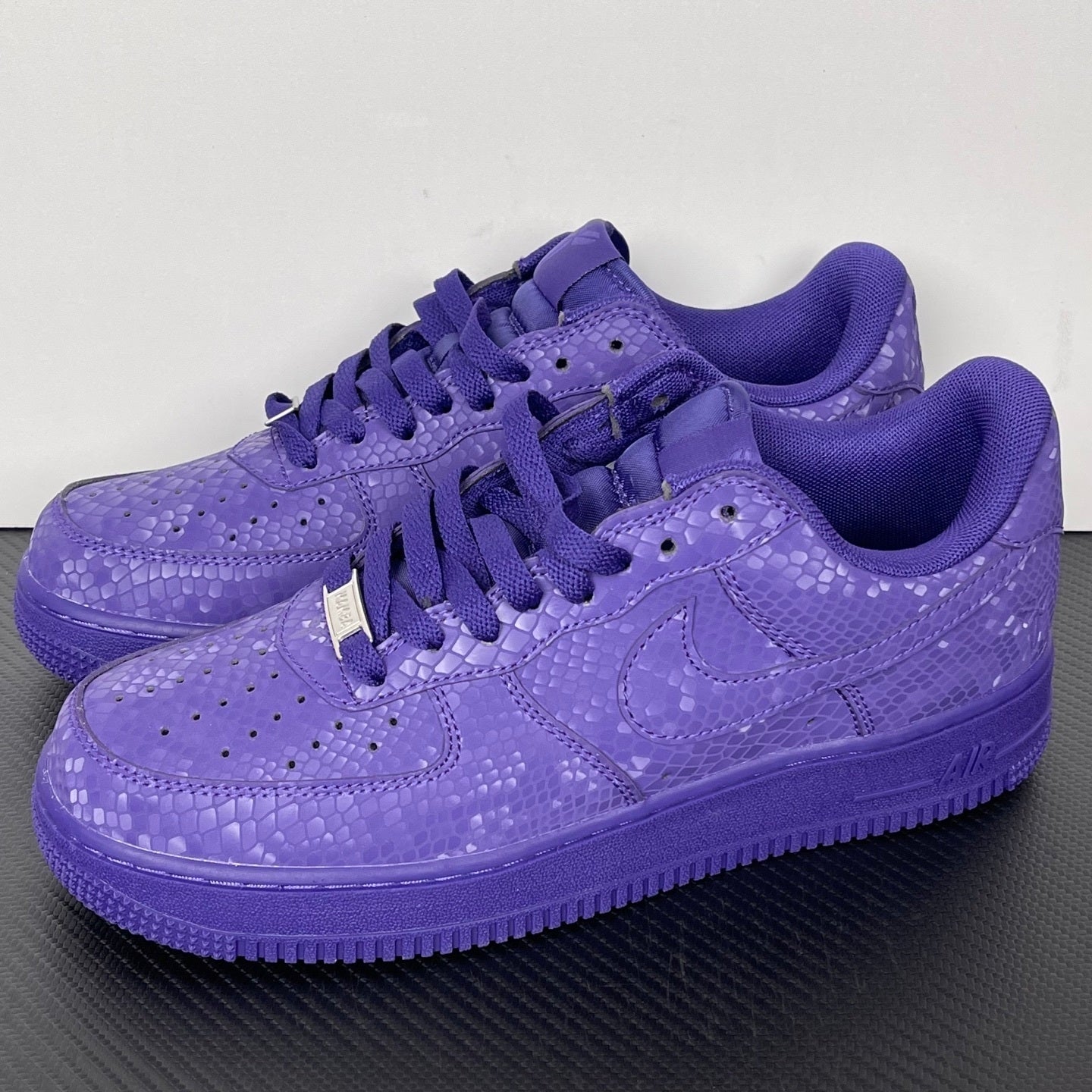 Pair of purple low-top sneakers with lace-up closure and embossed pattern