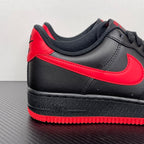 Black low-top sneaker with red swoosh stripe and textured black sole