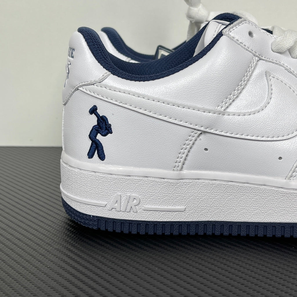 White Nike Air Force 1 low-top sneaker with navy swoosh and lace-up detail