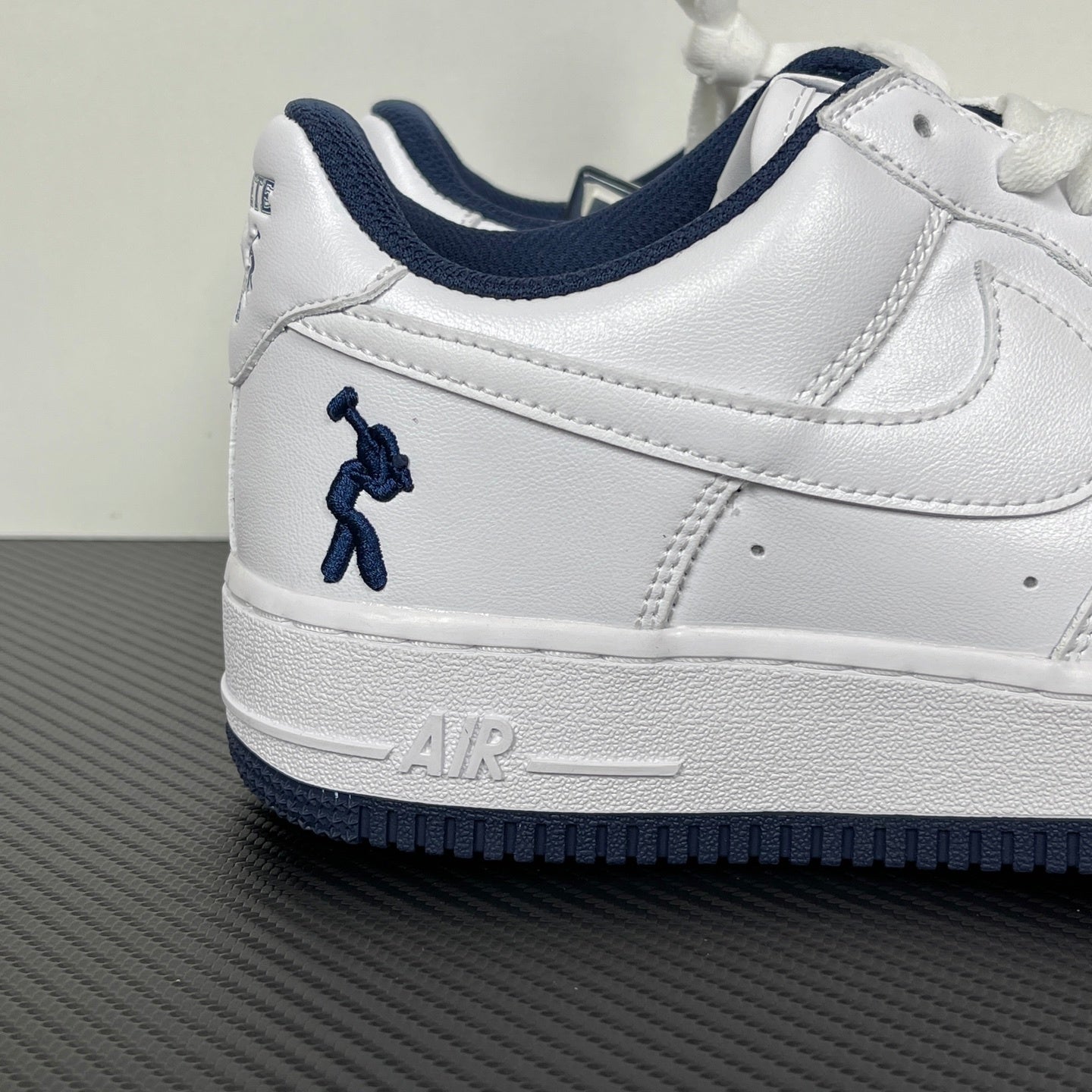 White Nike Air Force 1 low-top sneaker with navy swoosh and lace-up detail