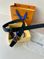 Dark navy croc belt with interlaced buckle, resting on box and dust bag