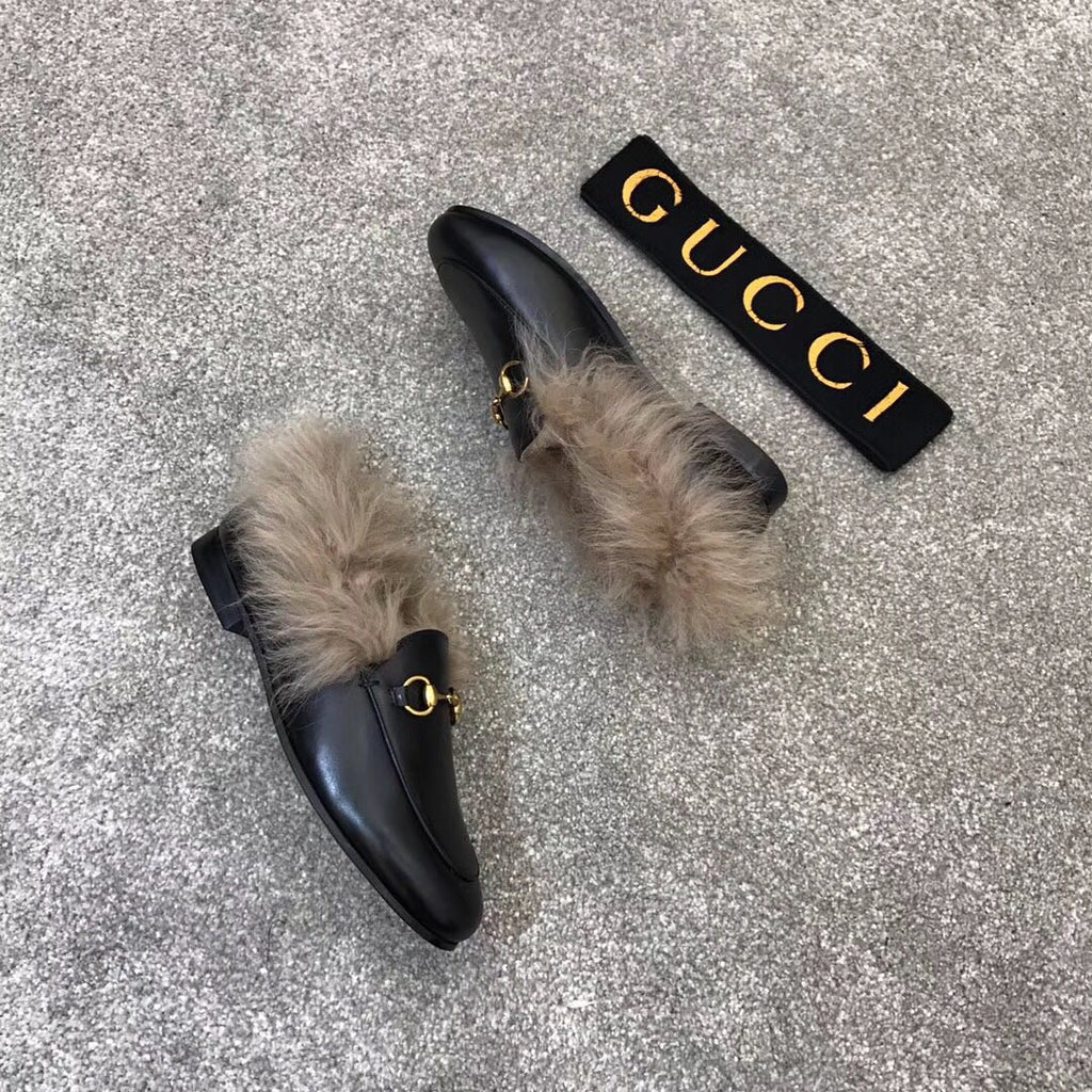 Gucci black loafer with faux fur cuff and gold bit hardware, angled view