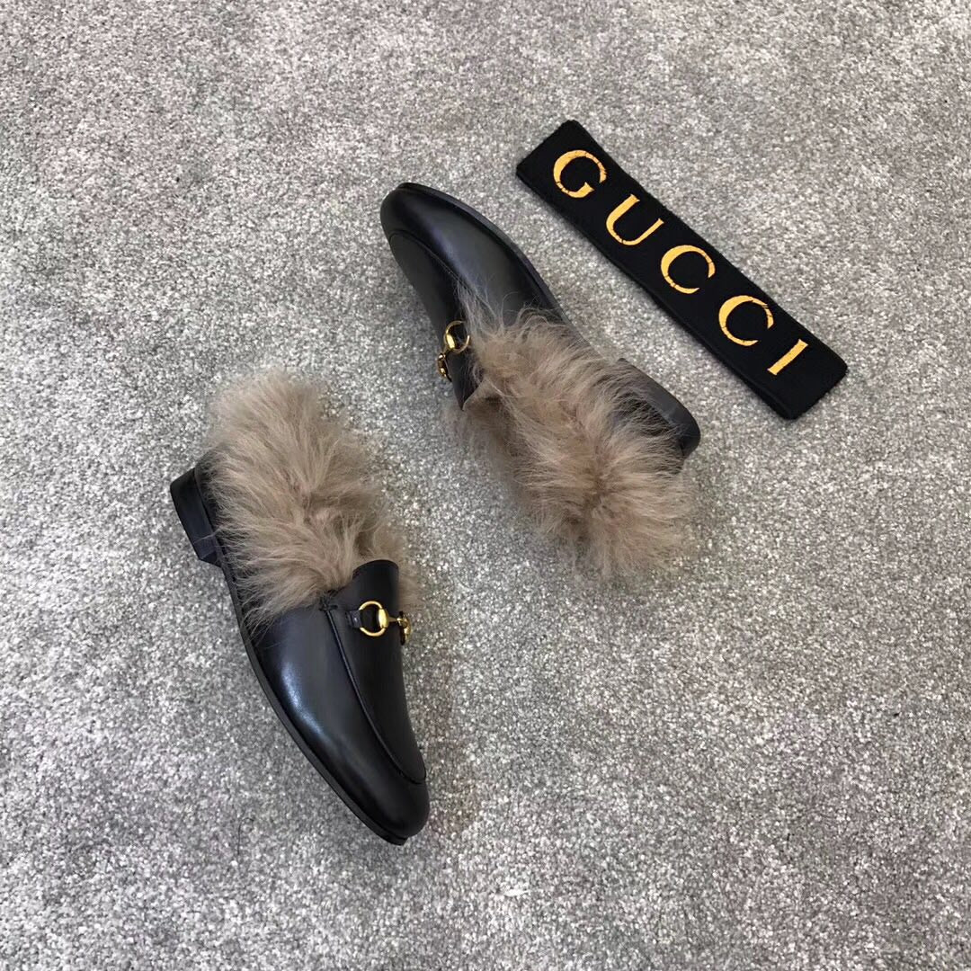 Gucci black loafer with faux fur cuff and gold bit hardware, angled view