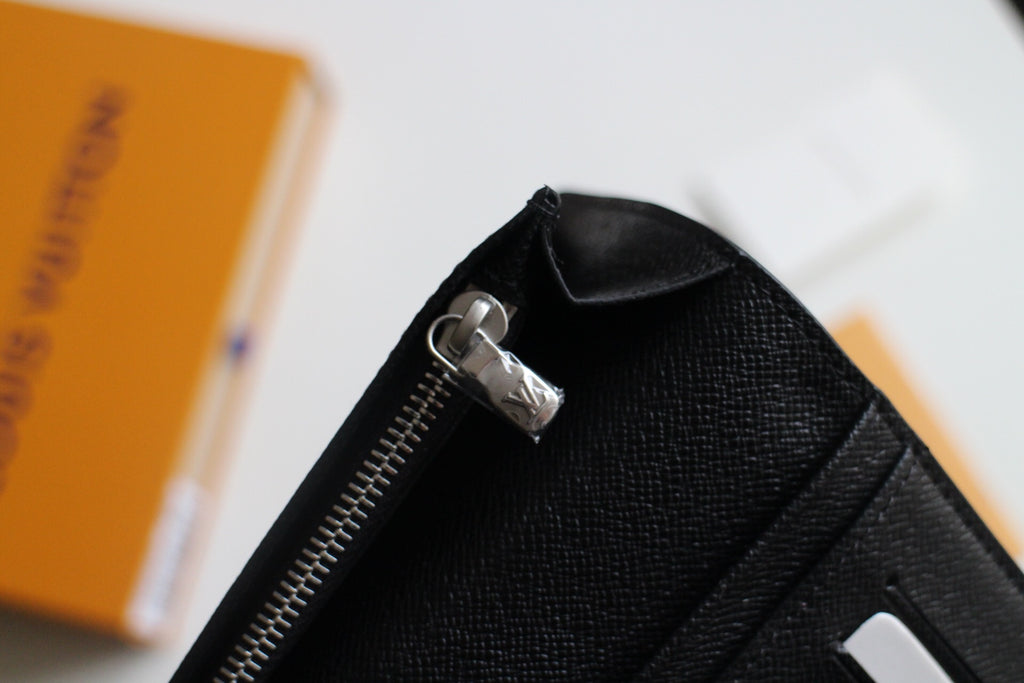 Louis Vuitton small wallet zipper pull on black leather, open edge visible
