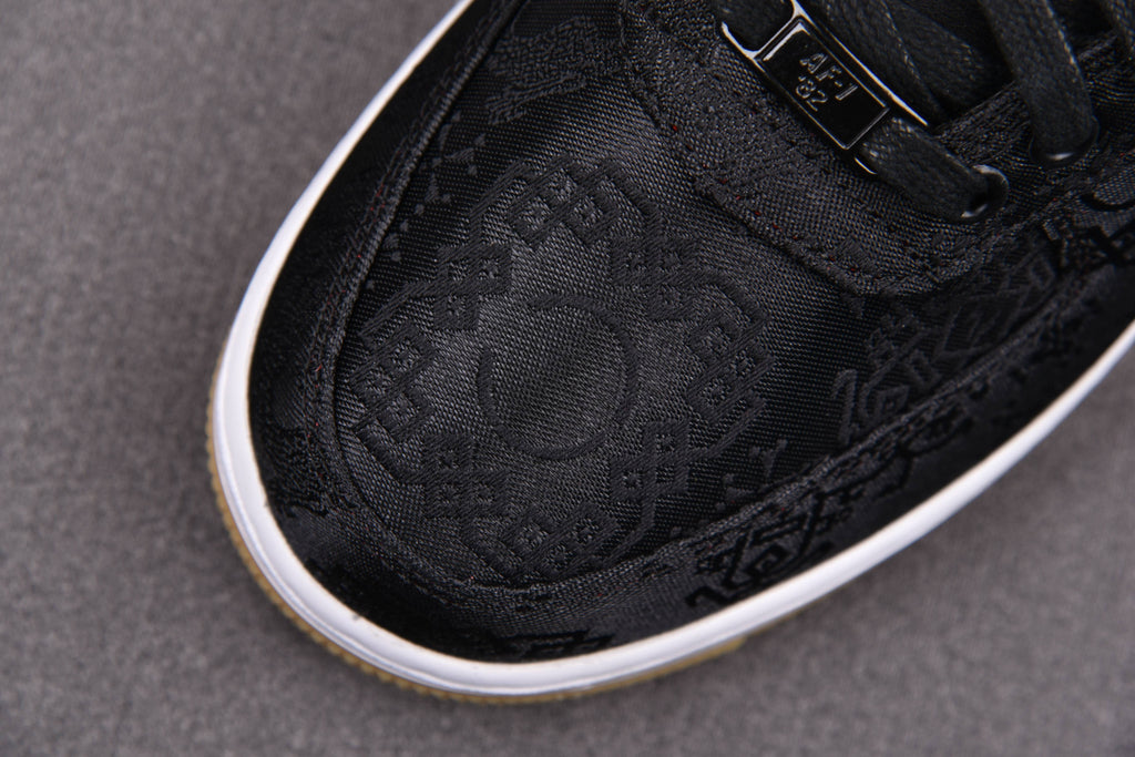 Black low-top sneakers with embossed monogram pattern and white edge sole