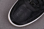 Black low-top sneakers with embossed monogram pattern and white edge sole