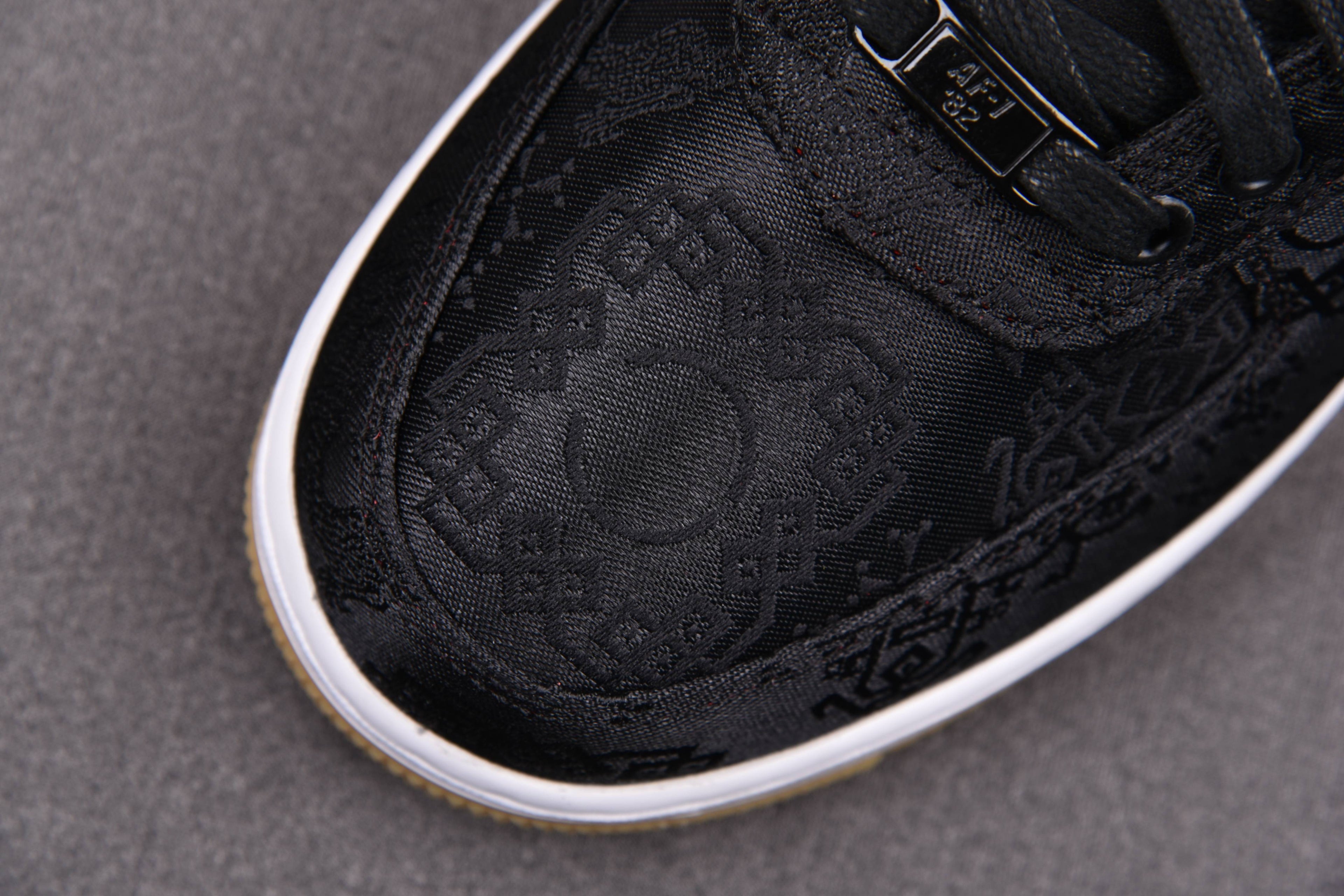 Black low-top sneakers with embossed monogram pattern and white edge sole