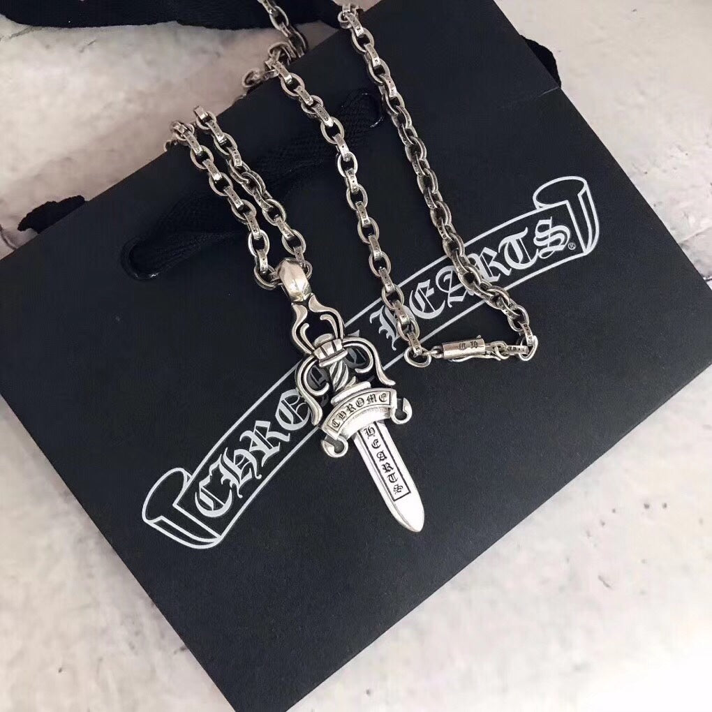 Chrome accessories necklace with silver chain and dagger pendant, on black pouch