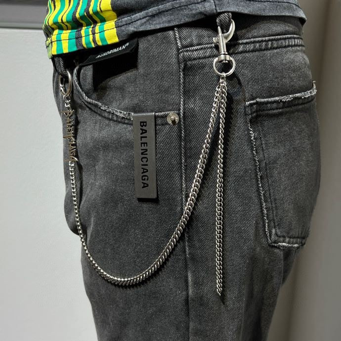 Silver-tone chain keychain hanging on dark jeans with label showing