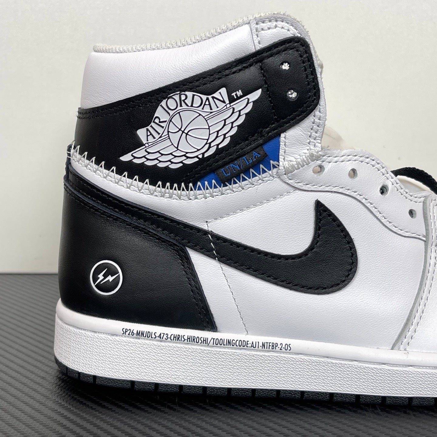 White and black high-top sneakers with black collar patch, blue accent, and Nike Swoosh
