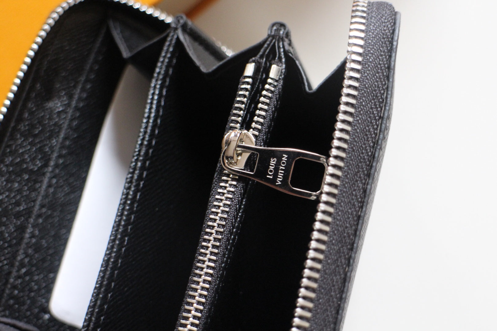 Dark textured leather wallet interior with card slots and zipper compartment