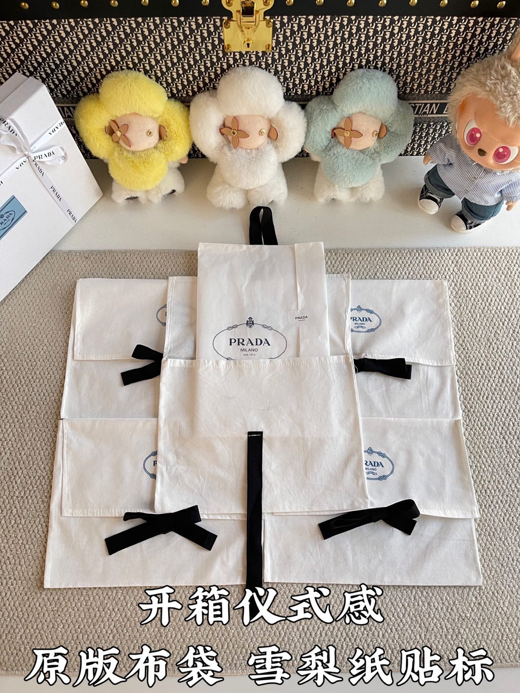 Multiple white Prada gift bags with black ribbon bows, arranged in a stack