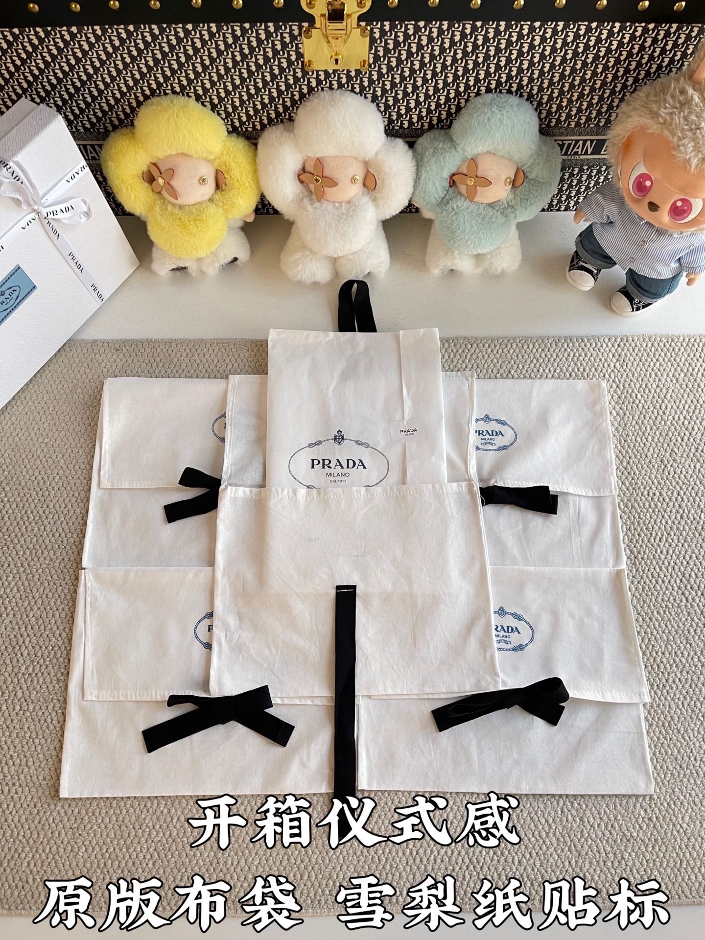 Multiple white Prada gift bags with black ribbon bows, arranged in a stack