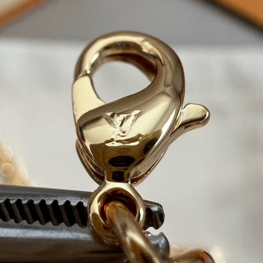 Gold-tone lobster clasp with ring and attachment, shown in tight close-up.