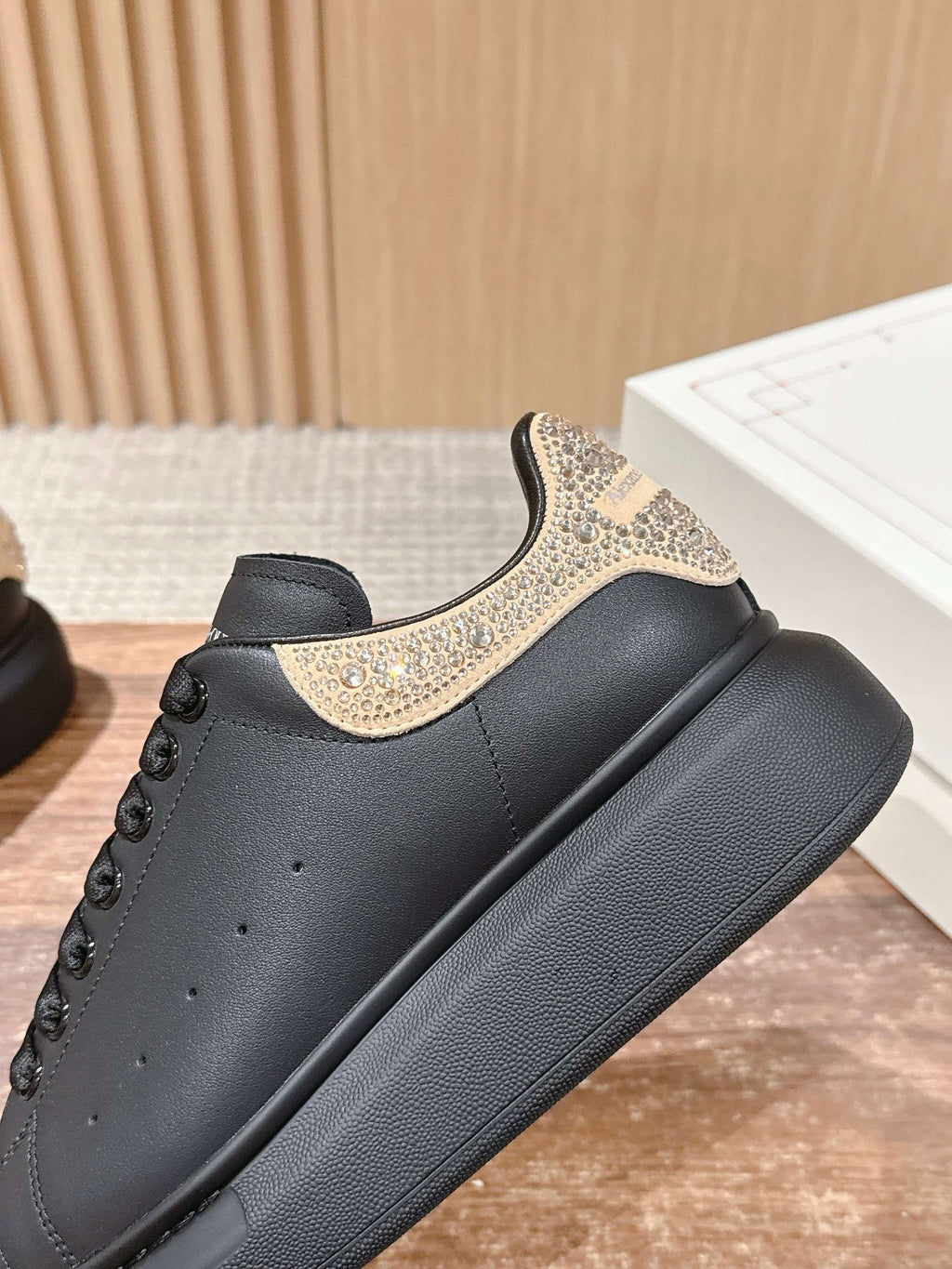 Side view of black leather sneakers with gold glitter decorative strap