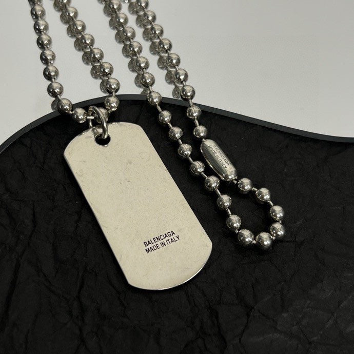 Dog tag pendant necklace with bead chains on dark fabric