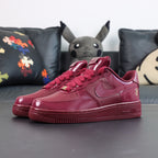 Burgundy low-top sneakers with glossy panels and Nike swoosh, front side view
