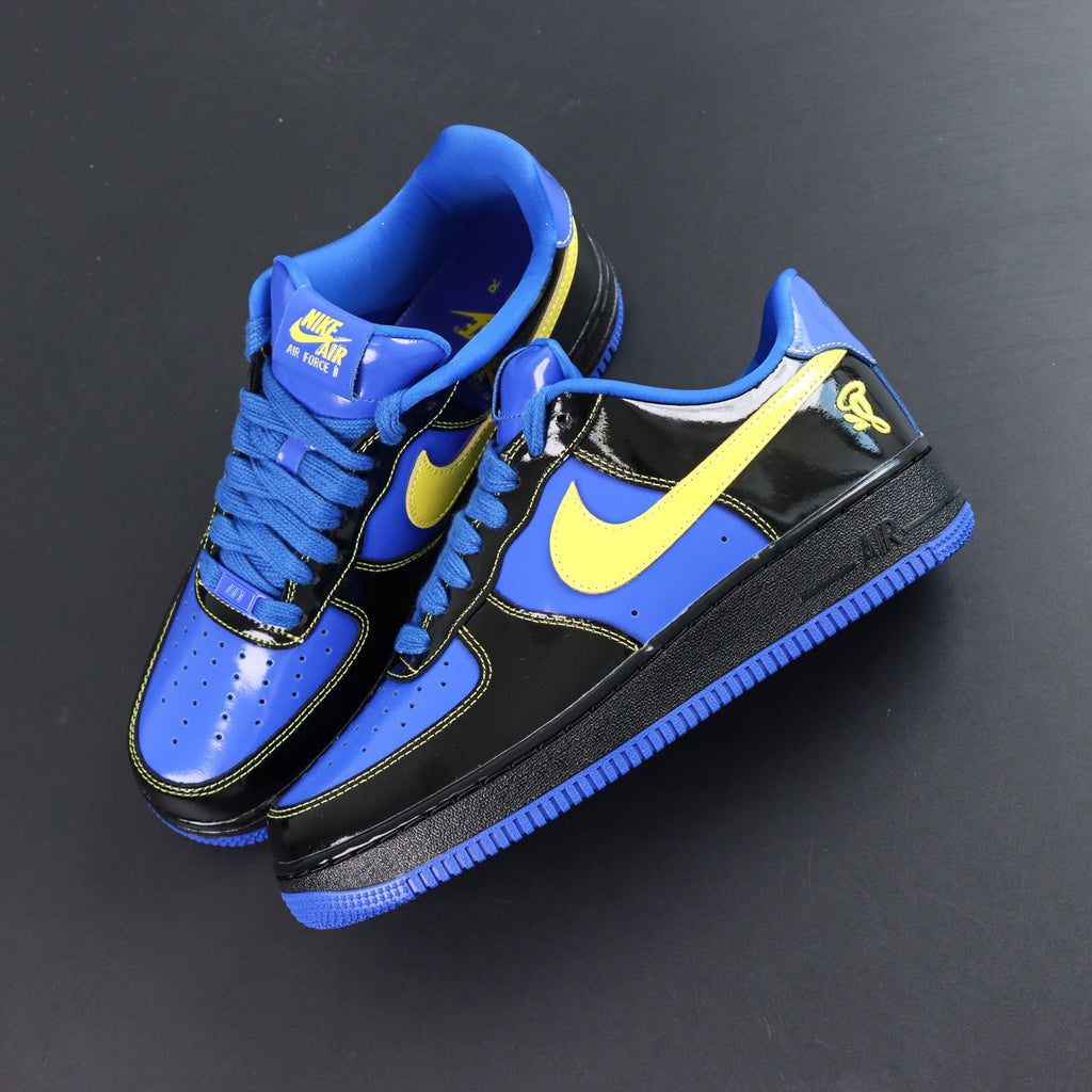 Nike Air Force 1 low-top sneakers, blue and black with yellow Swoosh; angled side view.