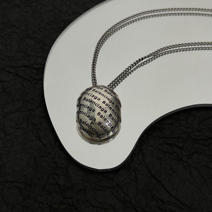 Round logo pendant necklace on white display plate with silver-tone chain