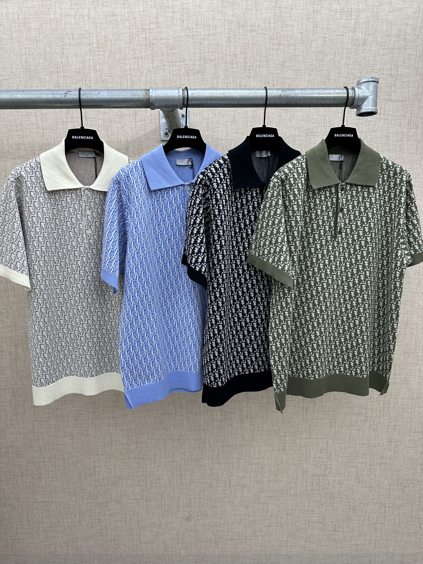 Four short-sleeve polo shirts on hangers: off-white, blue, black, dark green