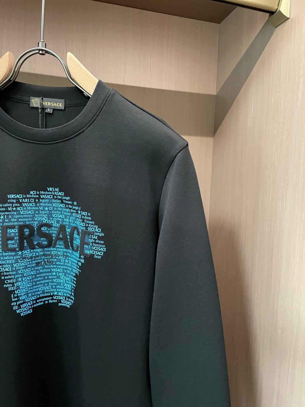 Black crewneck sweatshirt close-up of blue text face graphic