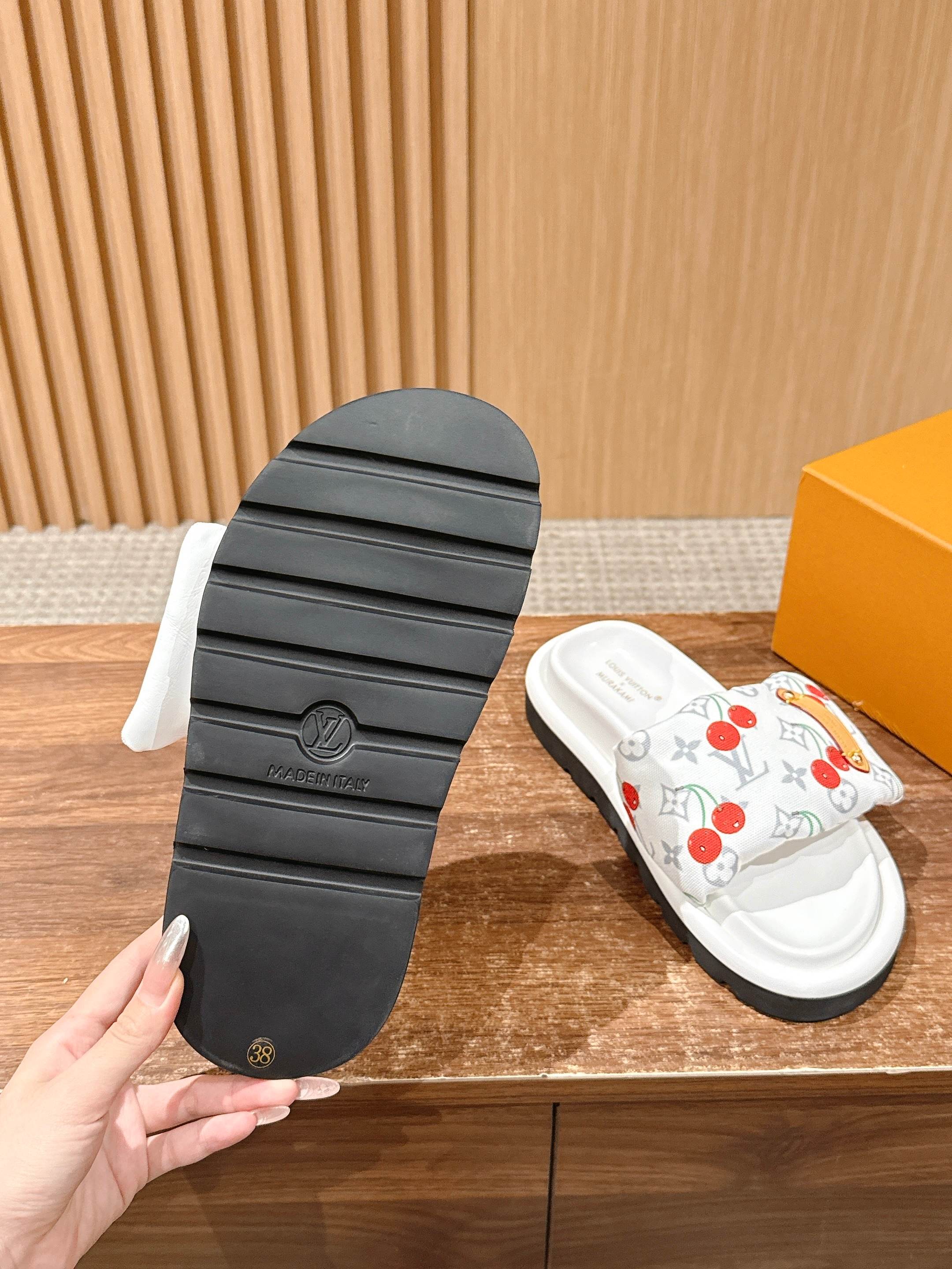 Slide sandal outsole view with black tread sole and white cherry-print upper