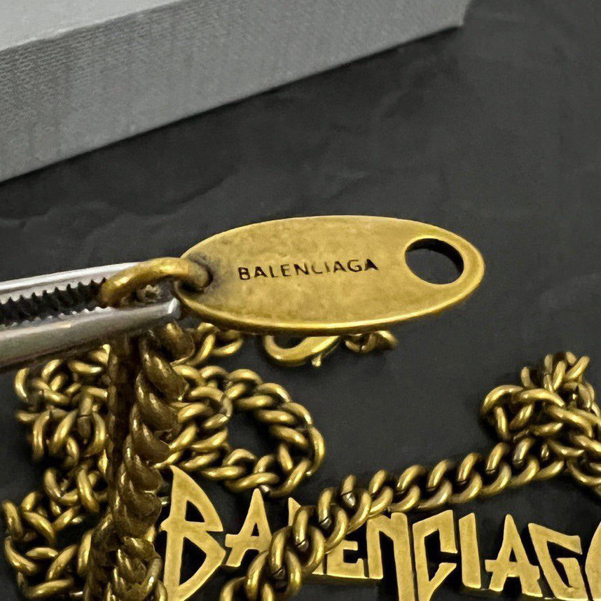 Gold Balenciaga oval charm tag with twisted chain and logo detail