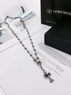 Silver-tone chain necklace with cross pendant on a black-and-white box