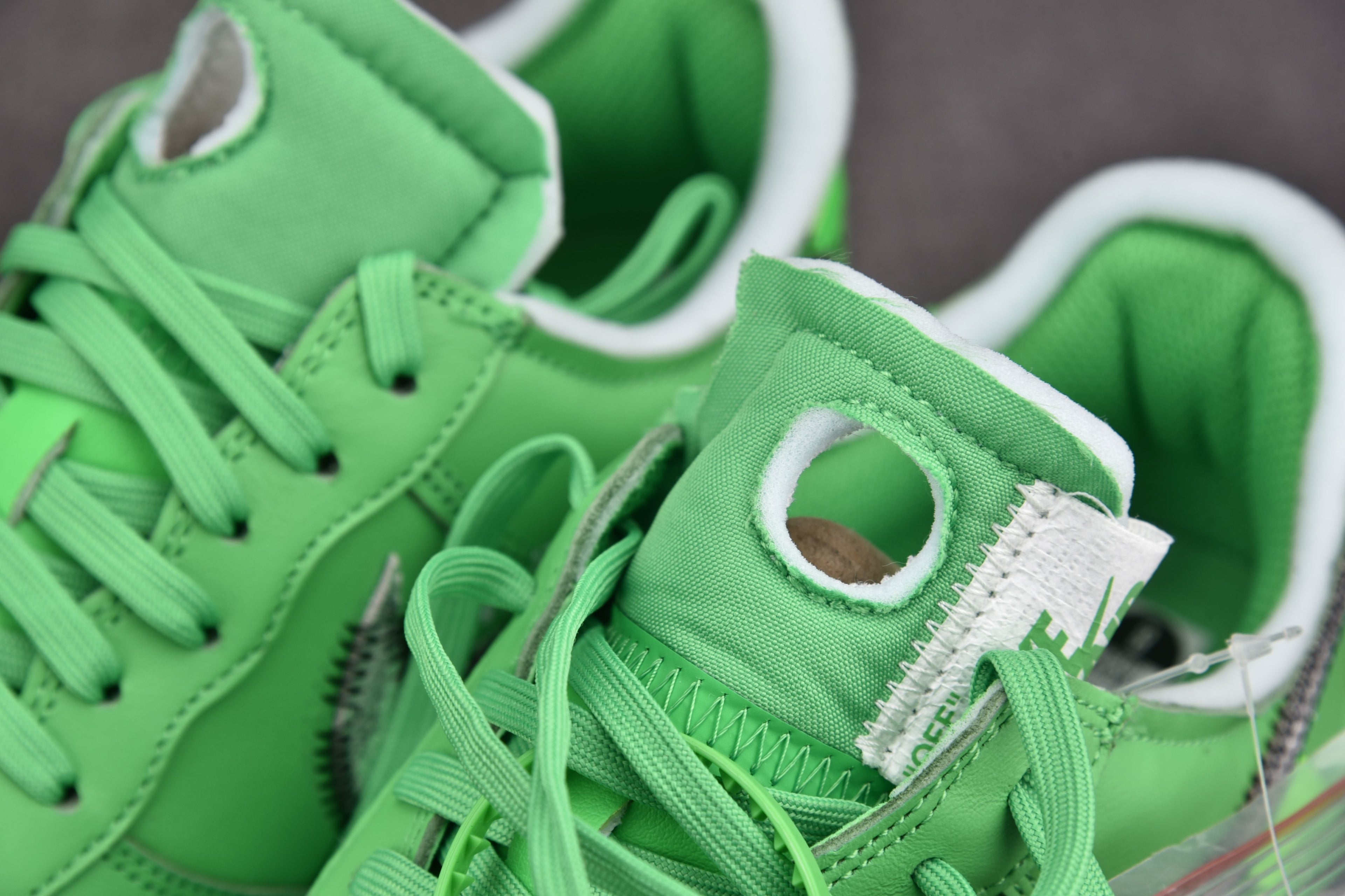 Green sneaker tongue and lace area with white collar and black logo patch