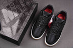 Black low-top sneakers with white midsoles and red-lined interior