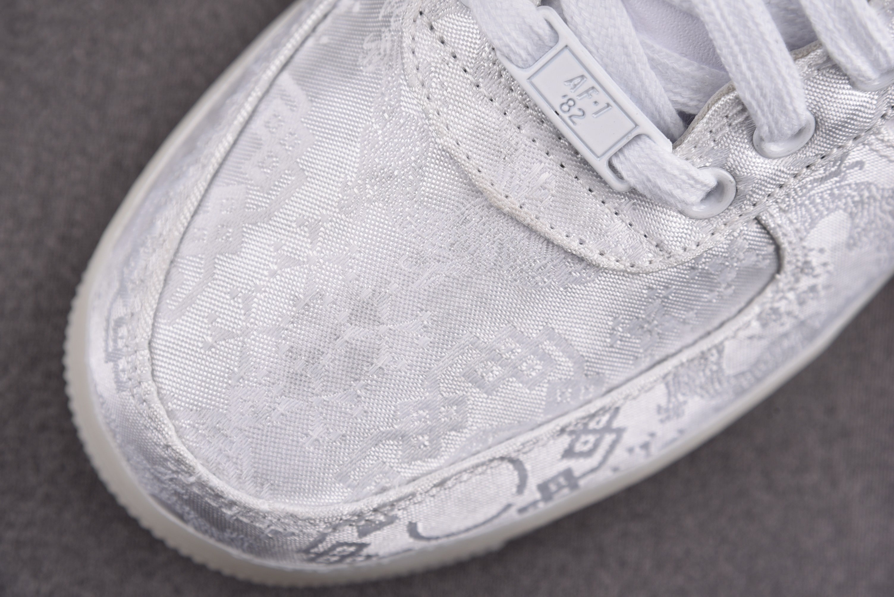 Close-up of white low-top sneakers with lace panel and embossed logos