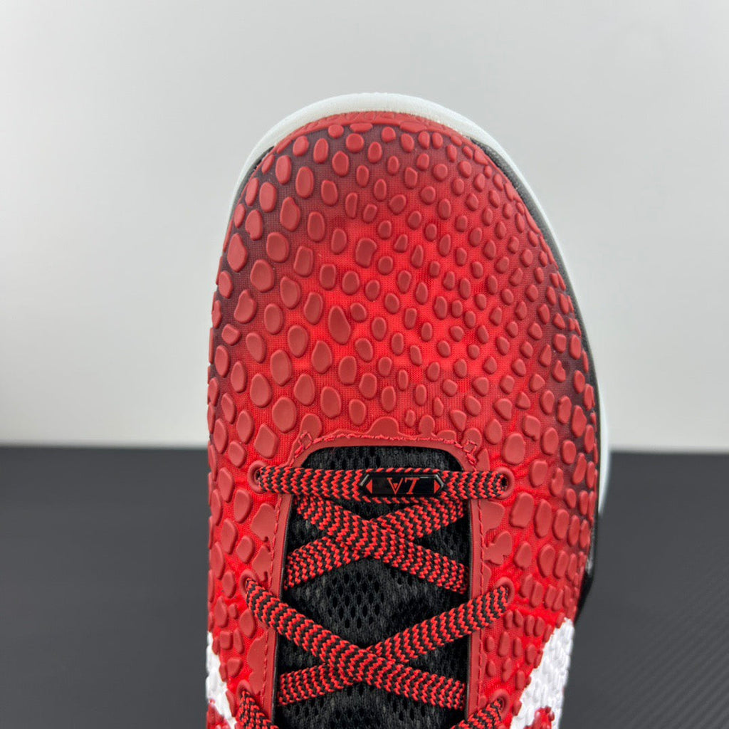 Close-up of red rubber shoe outsole with textured traction and black lace area.