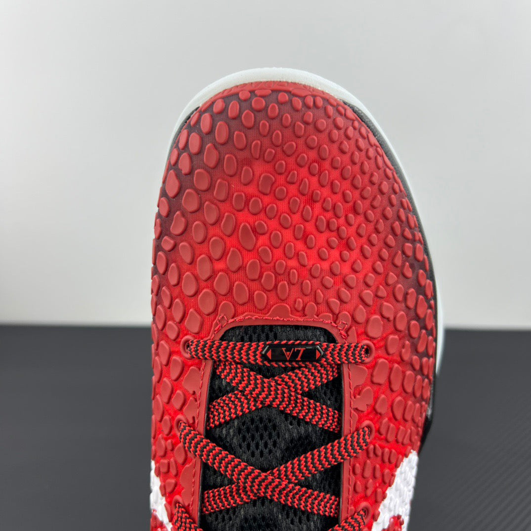 Close-up of red rubber shoe outsole with textured traction and black lace area.