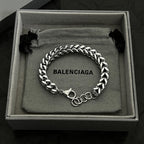 Silver chain bracelet with BALENCIAGA logo engraving and black tassel accents in box