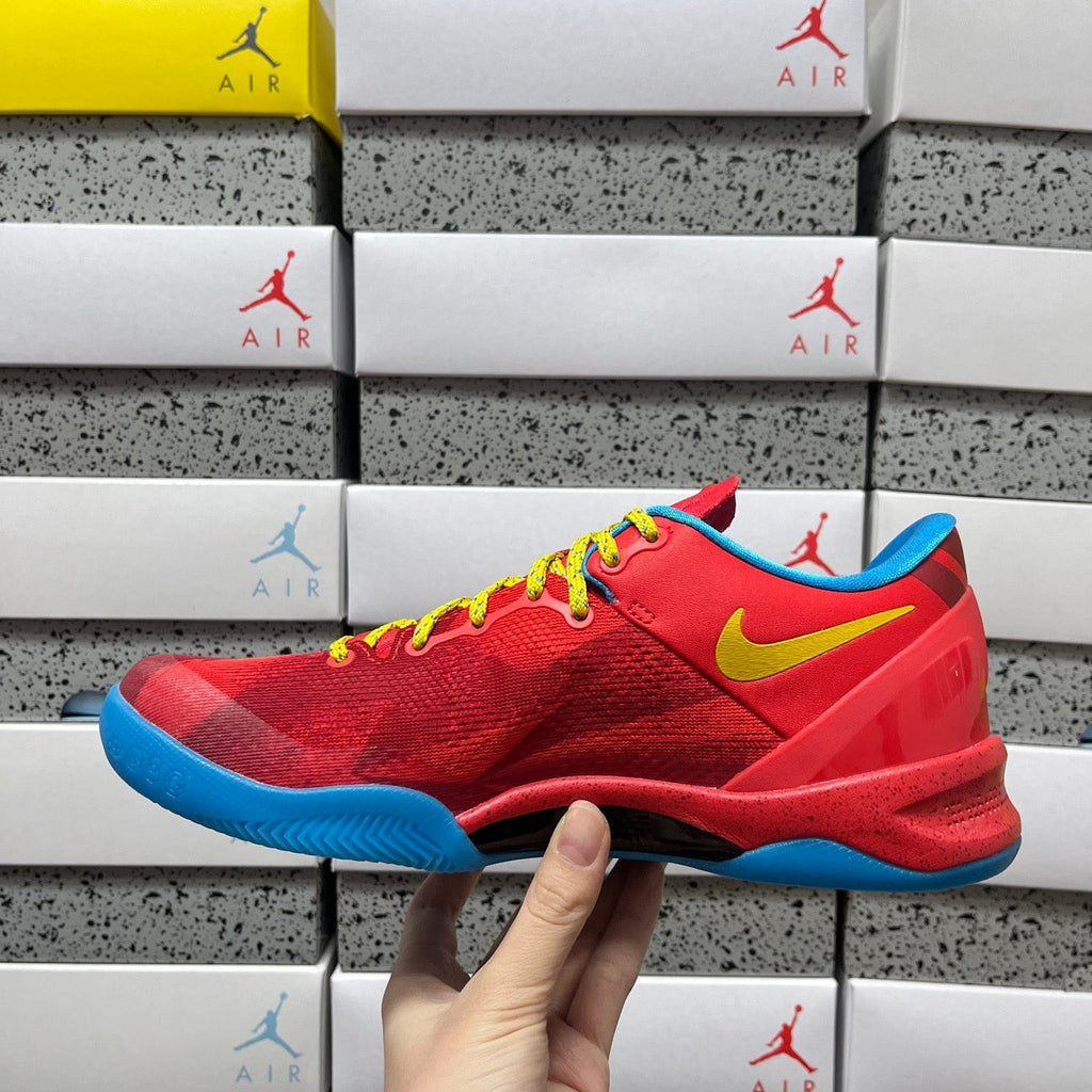 Red lace-up sneaker with yellow swoosh, blue sole, and textured upper.
