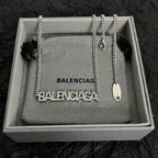 Silver Balenciaga logo pendant necklace with small charm detail in box