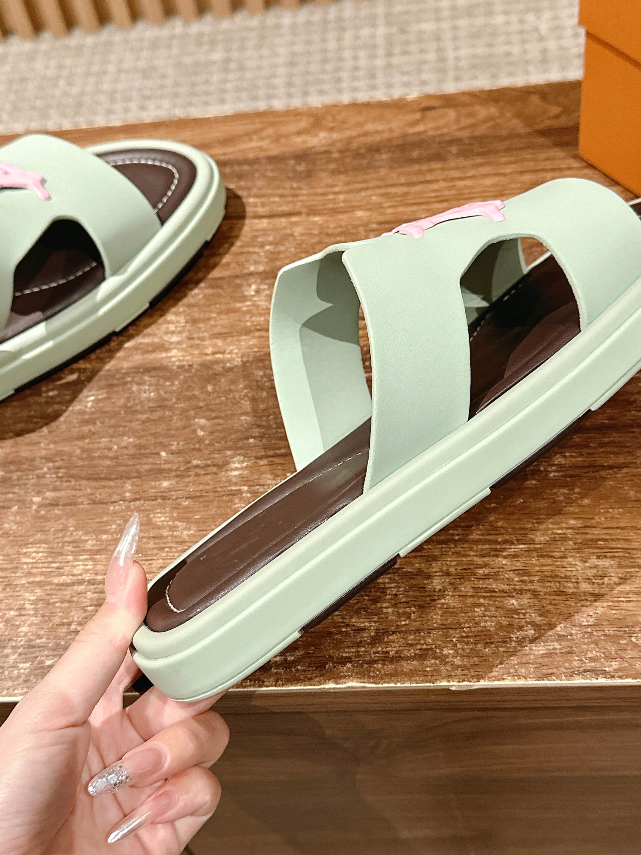Mint green Louis Vuitton slide sandal close-up with pink logo on dark footbed