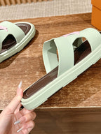 Close view of mint green slide sandal with brown footbed and pink strap logo