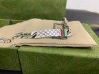 Silver chain bracelet with white leather tag and multicolor Gucci web stripe, close-up