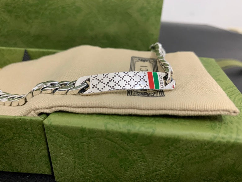 Silver chain bracelet with white leather tag and multicolor Gucci web stripe, close-up